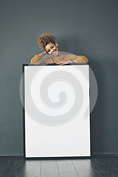 A beautiful confident woman holding a blank whiteboard or billboard sign with copy space. Happy and attractive female