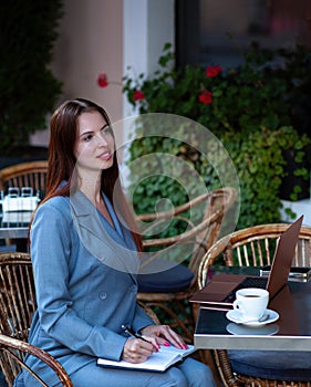 Beautiful confident woman. Woman on the street at the table . Business consultant, to note down, to make notes. Business