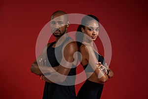 Beautiful and confident. Young african fitness couple in sportswear looking at camera while standing against red