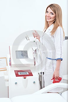 Beautiful cosmetician at her working place is going to apply procedure of laser epilation or rf lifting photo