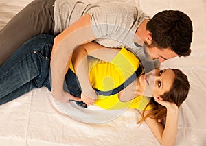 Beautiful coule - young man and pregnant woman resting on bed