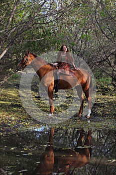 Beautiful country girl bareback ride her horse in autumn country road at sunset