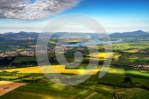 Beautiful country landscape with green, yellow fields and lake at background. Liptov, Slovakia