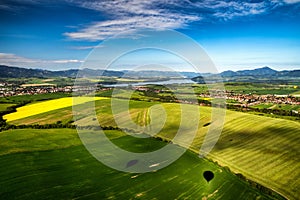 Beautiful country landscape with green, yellow fields and lake at background. Liptov, Slovakia