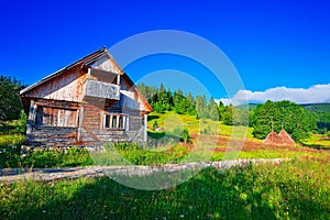 Beautiful countryside landscape with forested hills and haystacks on a grassy rural field in mountains