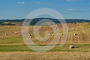 Beautiful countryside landscape near Siena in Tuscany, Italy. Round straw bales hay balls in harvested fields and blue sky.