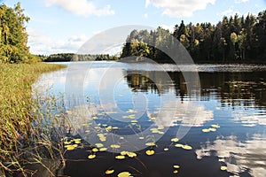 Beautiful countyside landscape with a river. Clouds are reflected in the water surface. Trees grow on the banks