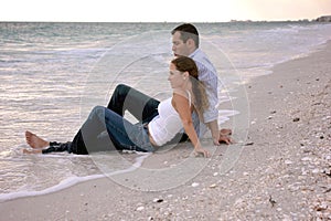 Beautiful couple at beach sitting in water clothed