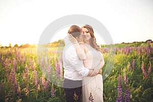 Beautiful couple, bride, groom kissing and hugging in the field sunset