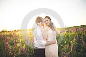 Beautiful couple, bride, groom kissing and hugging in the field sunset