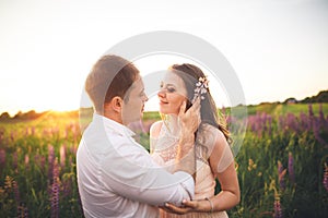 Beautiful couple, bride, groom kissing and hugging in the field sunset