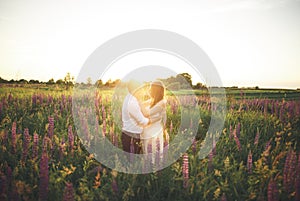 Beautiful couple, bride, groom kissing and hugging in the field sunset