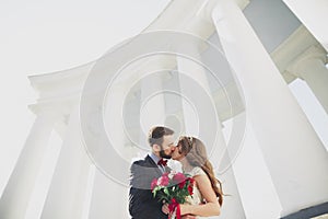 Beautiful couple, bride and groom posing near big white column