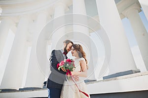 Beautiful couple, bride and groom posing near big white column