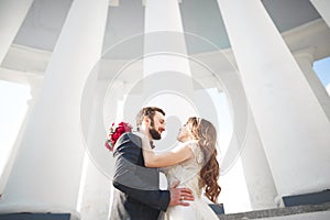 Beautiful couple, bride and groom posing near big white column