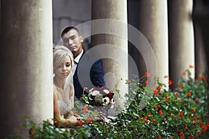Beautiful couple, bride and groom posing on old balcony with flo