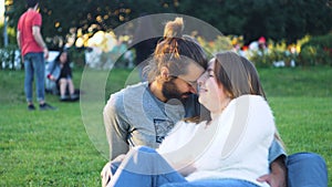 Beautiful couple caressing sitting on green grass in park. Concept. Happy young couple hugging on green grass in sun