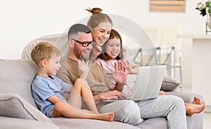 Father, mother and two cute children talking with family online