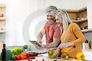 Beautiful couple cooking healthy dinner, checking recipes online