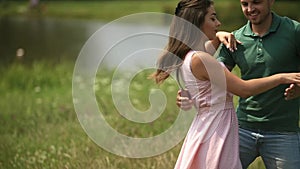 Beautiful couple dance in the field. the enjoy each other and smile. Summer weather. Romantic atmophere. slow motion