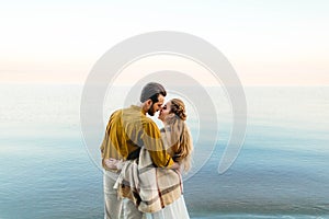A beautiful couple is embracing on the sea background. Moment before the kiss. Romantic date on the beach. View from the