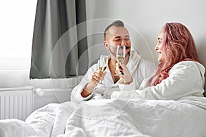 Beautiful couple have romantic time on bed drinking champagne