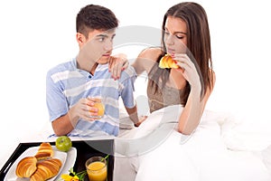 Beautiful couple having breakfast lying in the bed