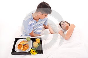 Beautiful couple having breakfast lying in the bed