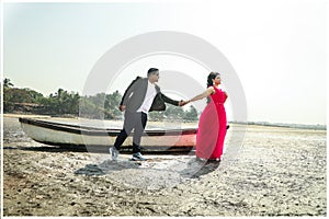 Beautiful couple holding hands by rowboat at beach