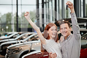 Beautiful couple is holding key of their new car, looking at camera and smiling