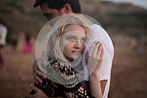 Beautiful couple hugging each other surrounded by hills under the sunlight at daytime