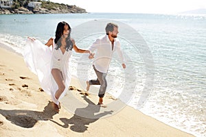 A beautiful couple just got married, enjoying running on the beach, husband holding his wife`s hand.