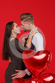 Beautiful couple kissing and hugging each other on a red background. The concept of Valentine`s Day.