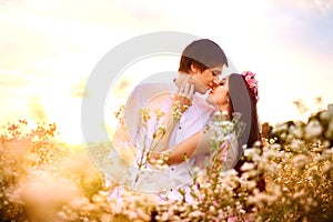 Beautiful couple kissing on nature in a yellow field of wheat in