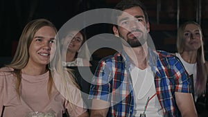 Beautiful couple laughing and whispering to her man during a film at the movie theatre