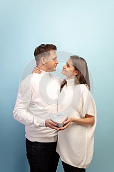 Beautiful couple in love on blue studio background. Valentine& x27;s Day, love and emotions concept