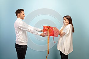 Beautiful couple in love on blue studio background. Valentine's Day, love and emotions concept