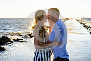 beautiful couple in love hugging and kissing on seashore during sunset