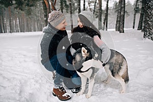 Couple in love with Husky dog walking in winter forest