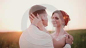Beautiful couple in love kiss in the nature on their wedding day in summertime. Wonderful sunset in countryside.