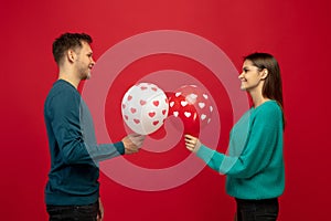 Beautiful couple in love on red studio background. Valentine's Day, love and emotions concept