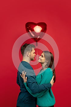 Beautiful couple in love on red studio background. Valentine's Day, love and emotions concept