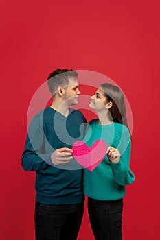 Beautiful couple in love on red studio background. Valentine's Day, love and emotions concept