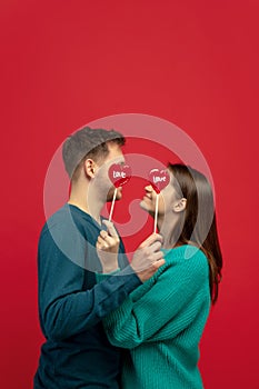 Beautiful couple in love on red studio background. Valentine's Day, love and emotions concept