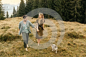 A beautiful couple in love are walking with the cat and smiling cheerfully in nature