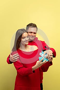 Beautiful couple in love on yellow studio background. Valentine's Day, love and emotions concept