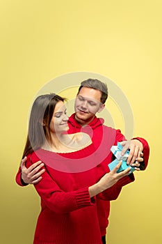 Beautiful couple in love on yellow studio background. Valentine's Day, love and emotions concept