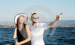 Beautiful couple of lovers sailing on a boat. Two fashion models posing on a sailing boat at sunset