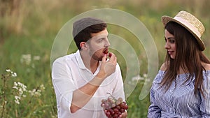 Beautiful couple man and pregnant woman eat red grapes. Healthy food. Fresh fruits. Happy woman smile