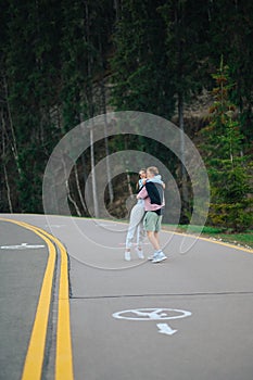 Beautiful couple of man and woman embracing while walking on a trip in nature, standing on the road in the mountains on a